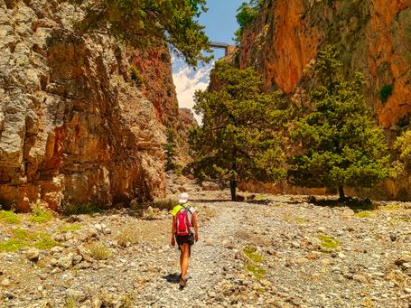 Wander und Genussreise in der Aradena Schlucht auf Kreta unter der Brücke geht eine Teilnehmerin mit Rucksack hindurch